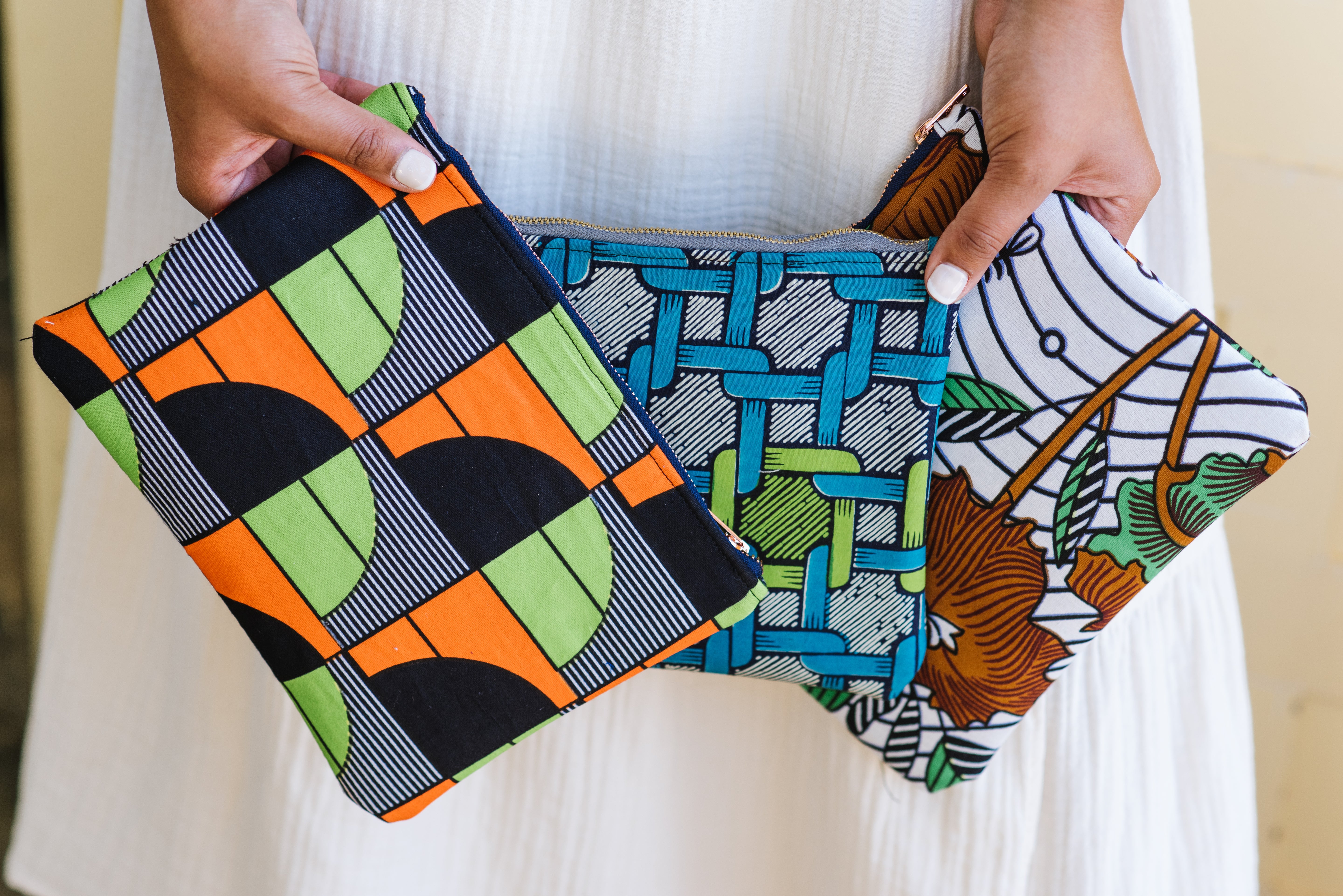 Woman holding three hand-dyed Zipper Clutch bag by GEOMETRIC.