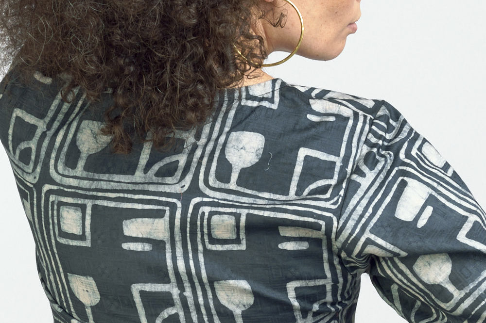 Woman wearing charcoal hand-dyed batik Coco print headband by Geometric with matching wrap shirt.