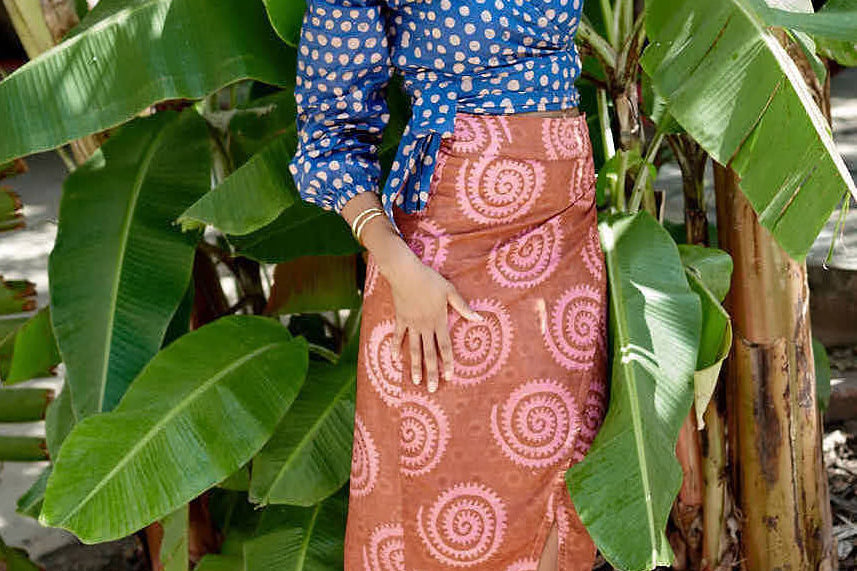 Woman wearing blue hand-dyed polka dot batik print wrap top and sea shell print wrap skirt by GEOMETRIC.