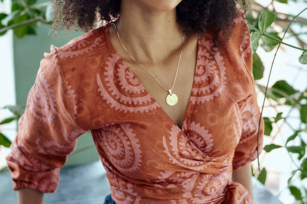 Woman wearing hand-dyed red and pink sea shell batik print long sleeve wrap top by GEOMETRIC.