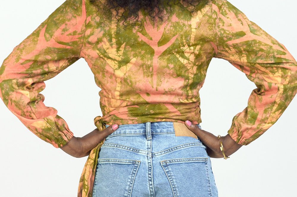 Back view of woman wearing hand-dyed orange Birds of Paradise batik print long sleeve wrap top by GEOMETRIC.