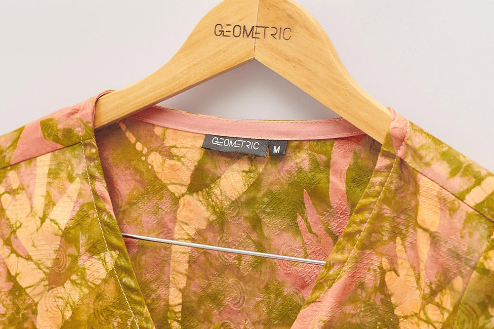 Close-up of hand-dyed orange Birds of Paradise batik print long sleeve wrap top by GEOMETRIC.