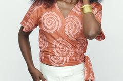 Woman wearing hand-dyed pink and orange Shea Shell dot batik print Short Sleeve Wrap Top by GEOMETRIC.