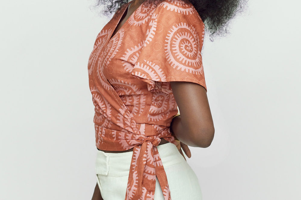 Woman wearing hand-dyed pink and orange Shea Shell dot batik print Short Sleeve Wrap Top by GEOMETRIC.