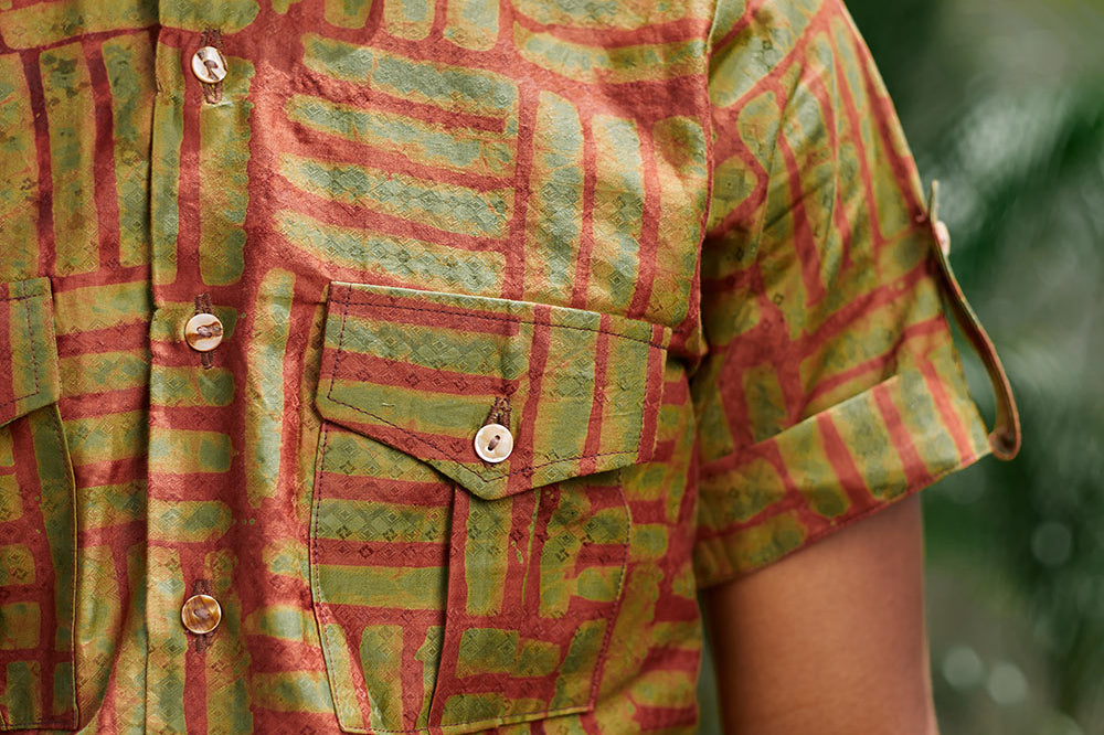 Close-up of man wearing hand-dyed green batik Garden Gate print short sleeve button up shirt by GEOMETRIC.
