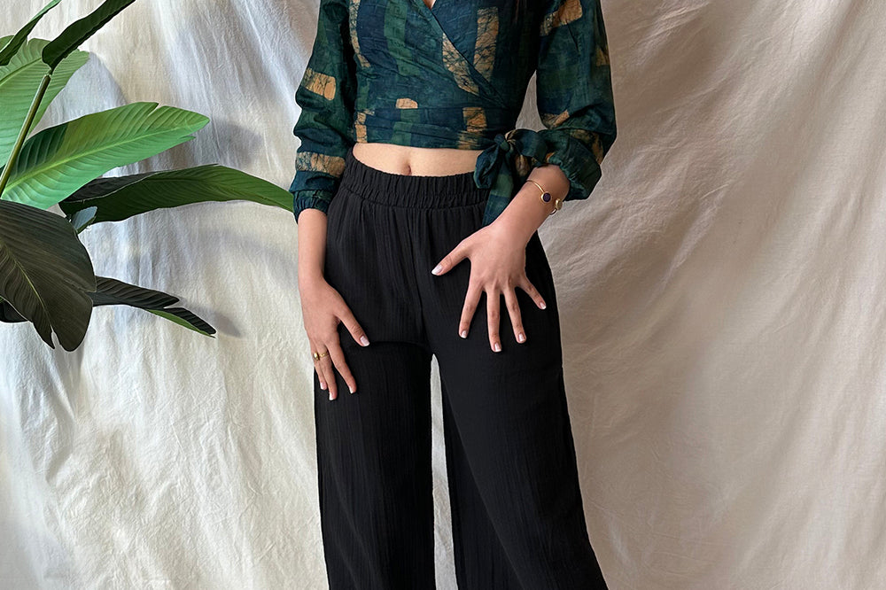 Woman wearing black pants and navy hand-dyed batik Brush Strokes print long sleeve wrap top by GEOMETRIC.