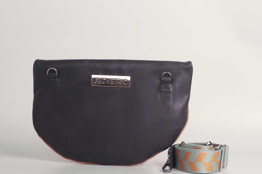 Back of dusty orange and black leather Crescent cross-body bag by GEOMETRIC. 