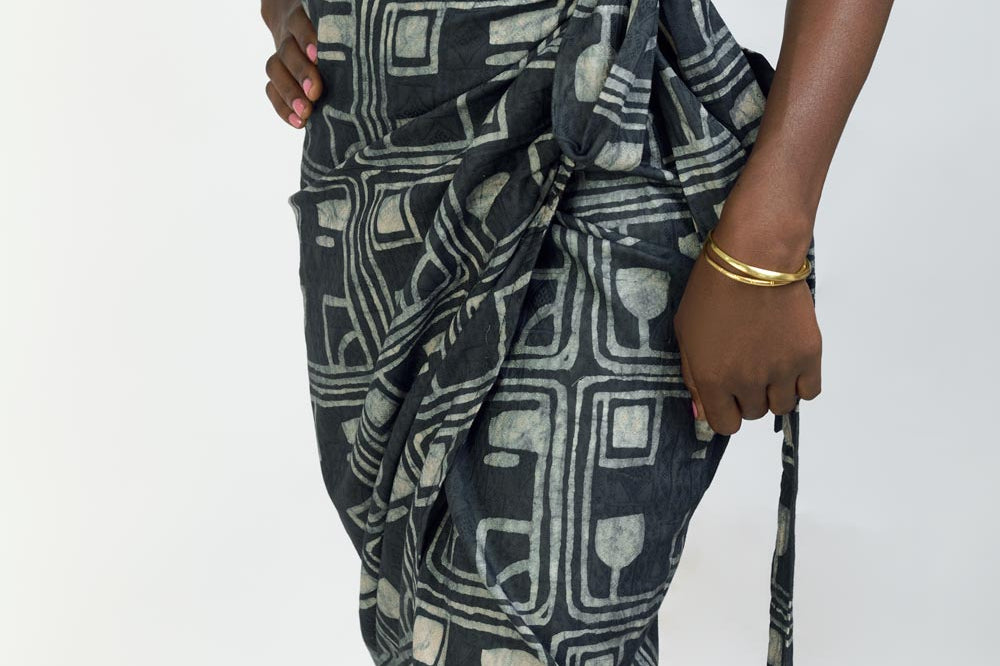 Close-up of woman wearing black tank top and charcoal hand-dyed Coco batik print Wrap Skirt by GEOMETRIC. 