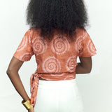 Back view of woman wearing hand-dyed pink and orange Shea Shell dot batik print Short Sleeve Wrap Top by GEOMETRIC. 