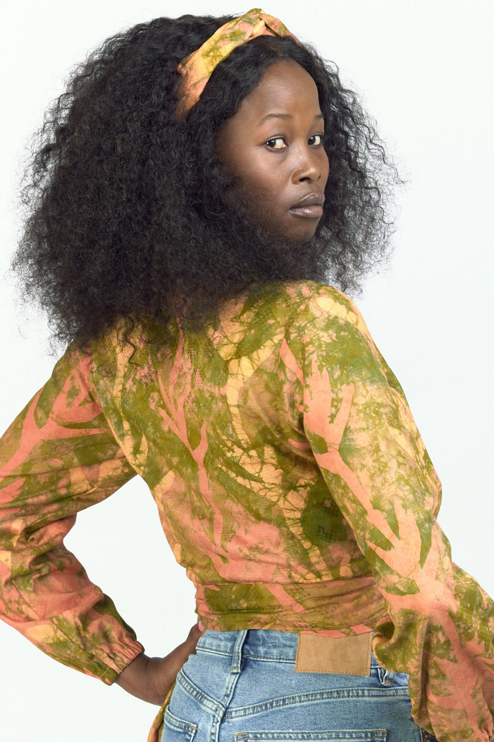 Woman wearing orange hand-dyed Birds of Paradise headband by GEOMETRIC with matching wrap top. 