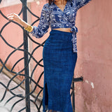 Woman wearing denim skirt and blue hand-dyed batik Coco print long sleeve wrap top by GEOMETRIC. 