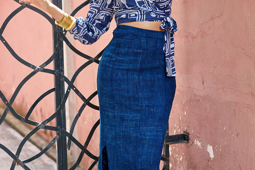 Woman wearing denim skirt and blue hand-dyed batik Coco print long sleeve wrap top by GEOMETRIC. 
