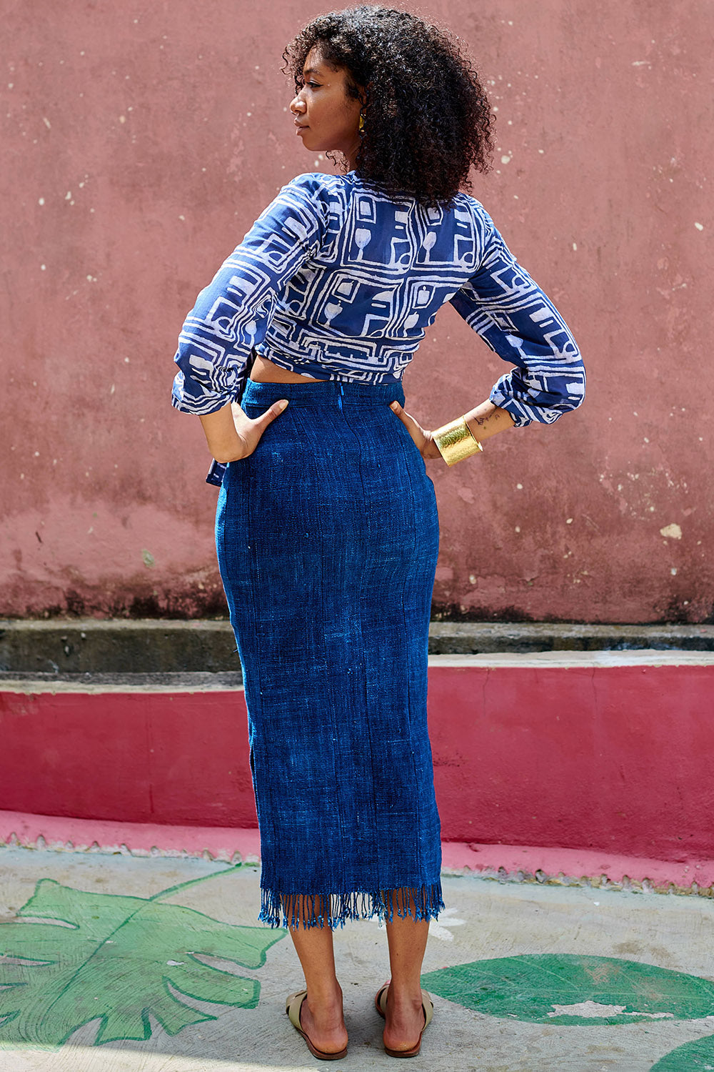 Back view of woman wearing denim skirt blue hand-dyed batik Coco print long sleeve wrap top by GEOMETRIC. 