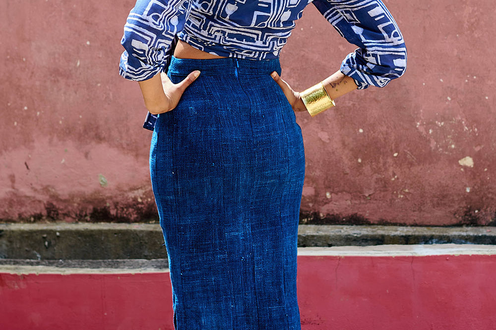 Back view of woman wearing denim skirt blue hand-dyed batik Coco print long sleeve wrap top by GEOMETRIC. 