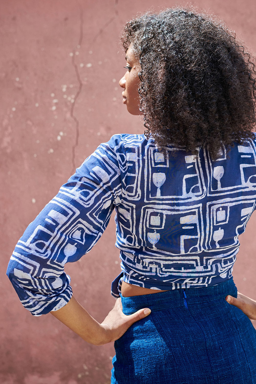 Back view of woman wearing blue hand-dyed batik Coco print long sleeve wrap top by GEOMETRIC. 