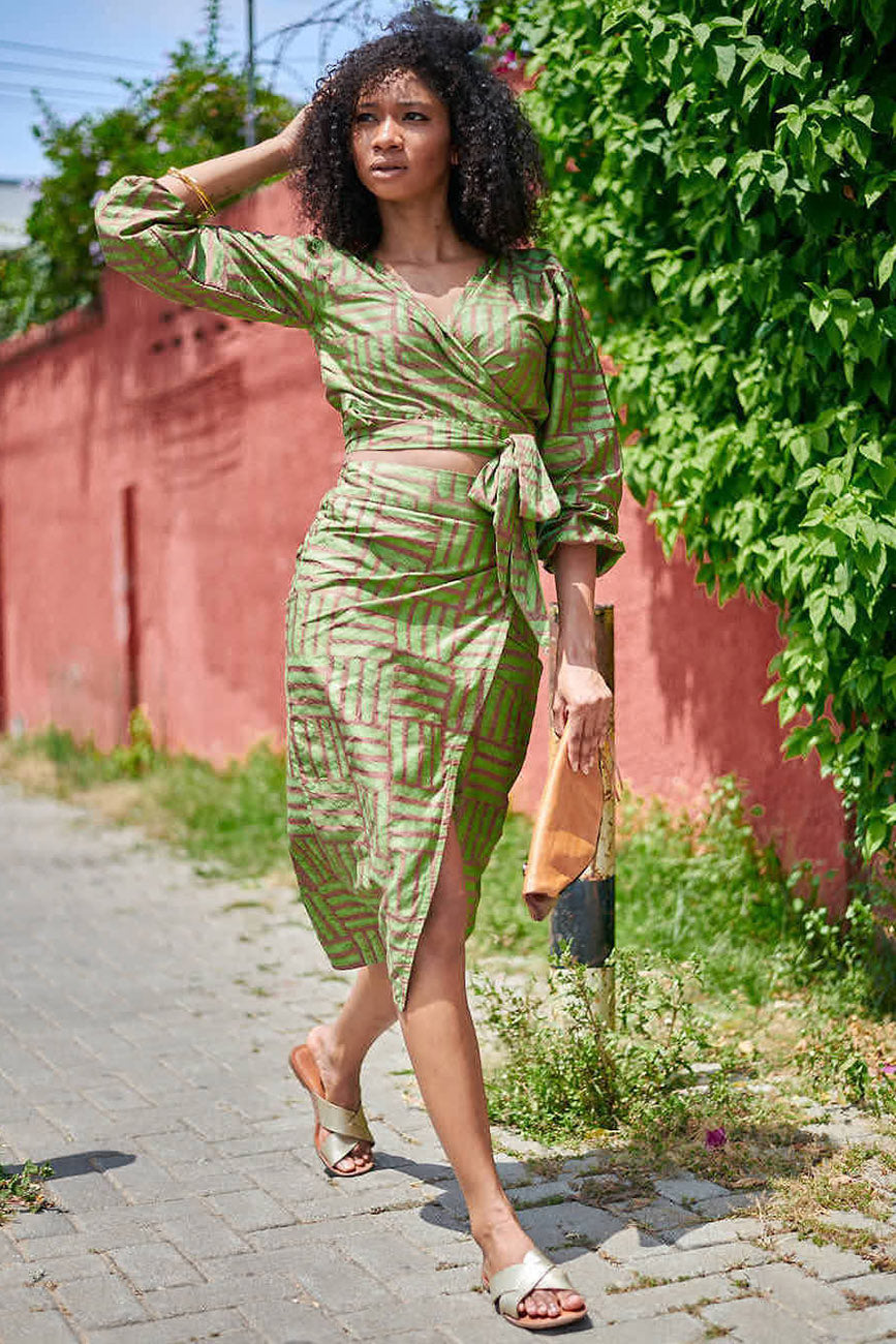 Woman wearing matching green hand-dyed batik Garden Party print long sleeve wrap top and wrap skirt by GEOMETRIC. 