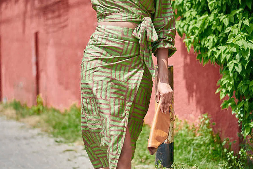 Woman wearing matching green hand-dyed batik Garden Party print long sleeve wrap top and wrap skirt by GEOMETRIC. 