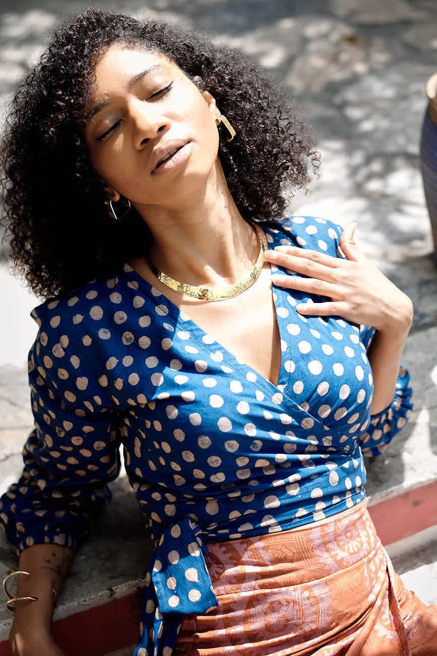 Woman wearing blue hand-dyed polka dot batik print wrap top by GEOMETRIC. 