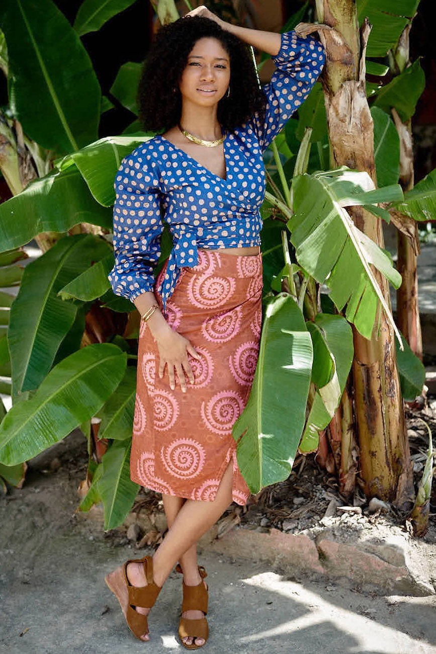 Woman wearing blue hand-dyed polka dot batik print wrap top and sea shell print wrap skirt by GEOMETRIC. 