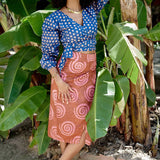 Woman wearing blue hand-dyed polka dot batik print wrap top and sea shell print wrap skirt by GEOMETRIC. 