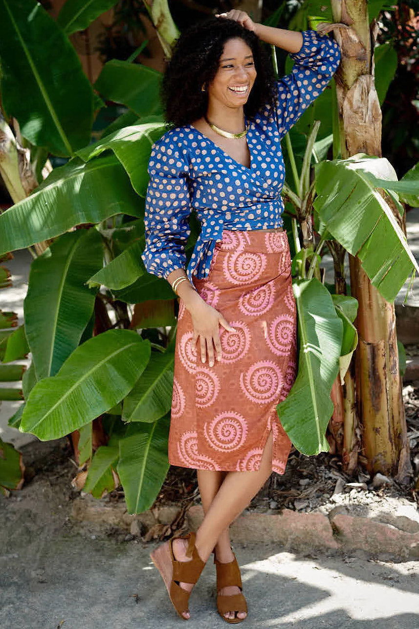 Woman wearing blue hand-dyed polka dot batik print wrap top and sea shell print wrap skirt by GEOMETRIC. 