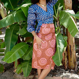 Woman wearing blue hand-dyed polka dot batik print wrap top and sea shell print wrap skirt by GEOMETRIC. 