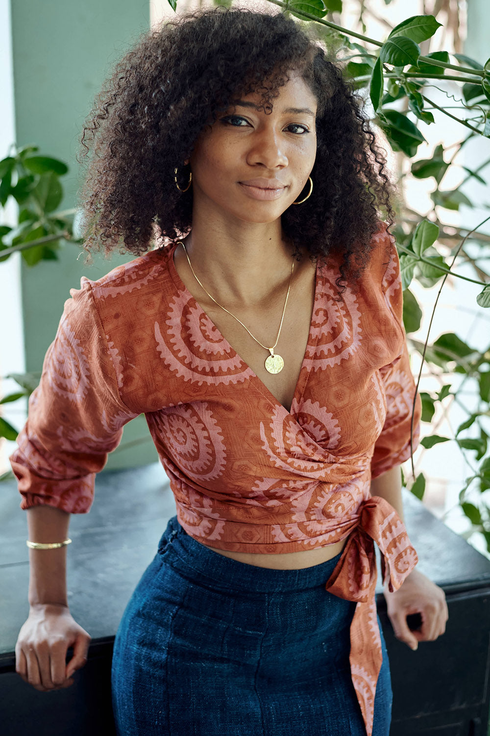 Woman wearing hand-dyed red and pink sea shell batik print long sleeve wrap top by GEOMETRIC. 