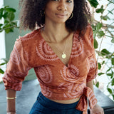 Woman wearing hand-dyed red and pink sea shell batik print long sleeve wrap top by GEOMETRIC. 