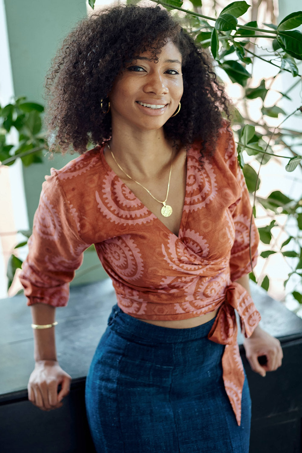 Woman wearing hand-dyed red and pink sea shell batik print long sleeve wrap top by GEOMETRIC. 