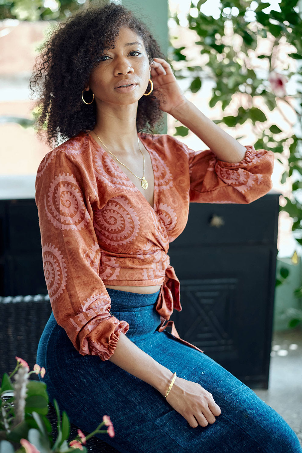 Woman wearing hand-dyed red and pink sea shell batik print long sleeve wrap top by GEOMETRIC. 