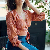 Woman wearing hand-dyed red and pink sea shell batik print long sleeve wrap top by GEOMETRIC. 