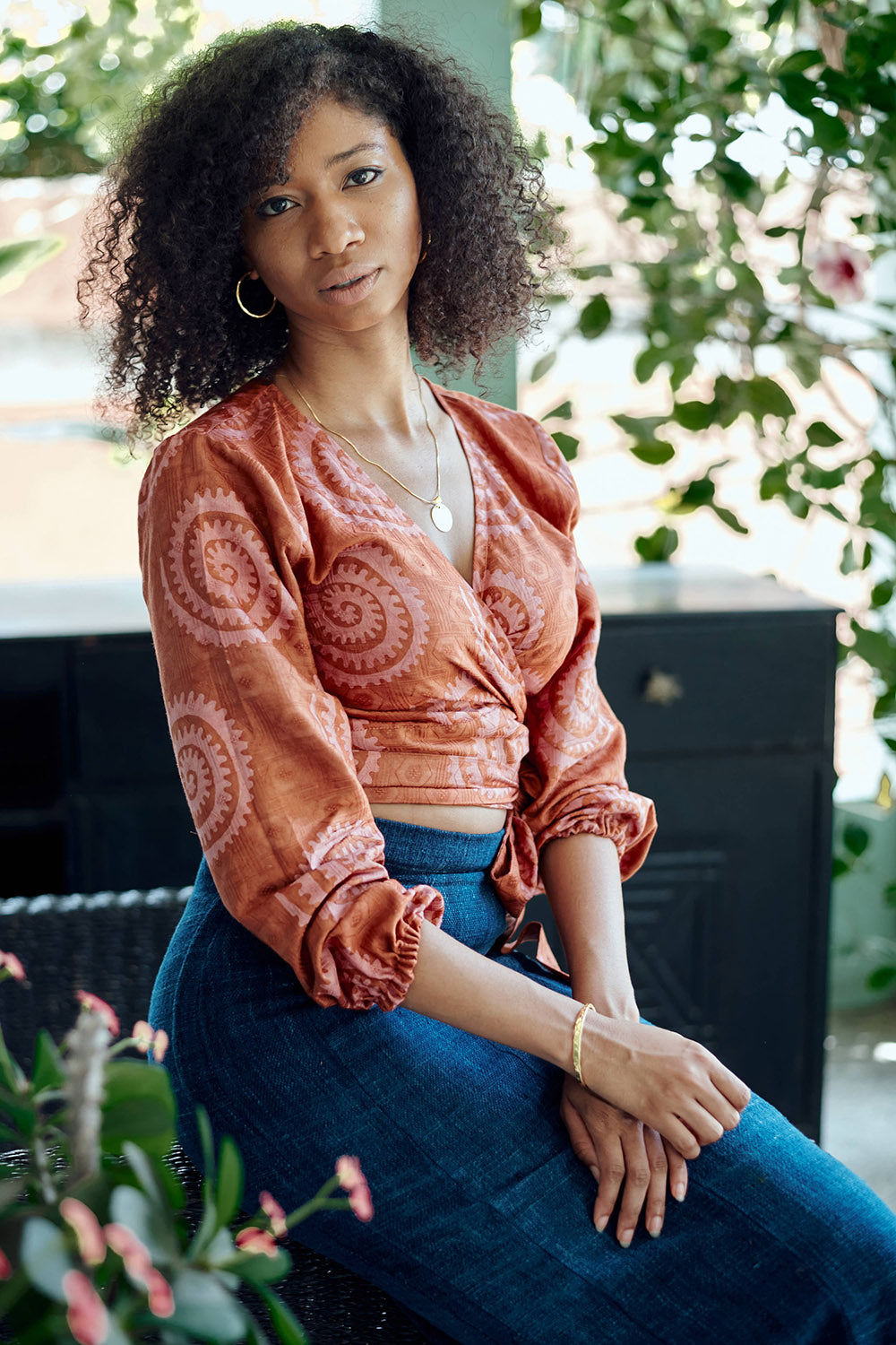 Woman wearing hand-dyed red and pink sea shell batik print long sleeve wrap top by GEOMETRIC. 