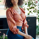 Woman wearing hand-dyed red and pink sea shell batik print long sleeve wrap top by GEOMETRIC. 