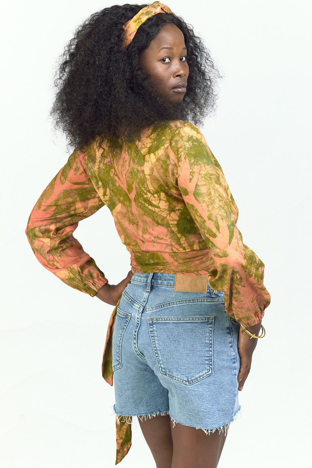 Woman wearing hand-dyed orange Birds of Paradise batik print long sleeve wrap top by GEOMETRIC. 