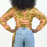 Back view of woman wearing hand-dyed orange Birds of Paradise batik print long sleeve wrap top by GEOMETRIC. 