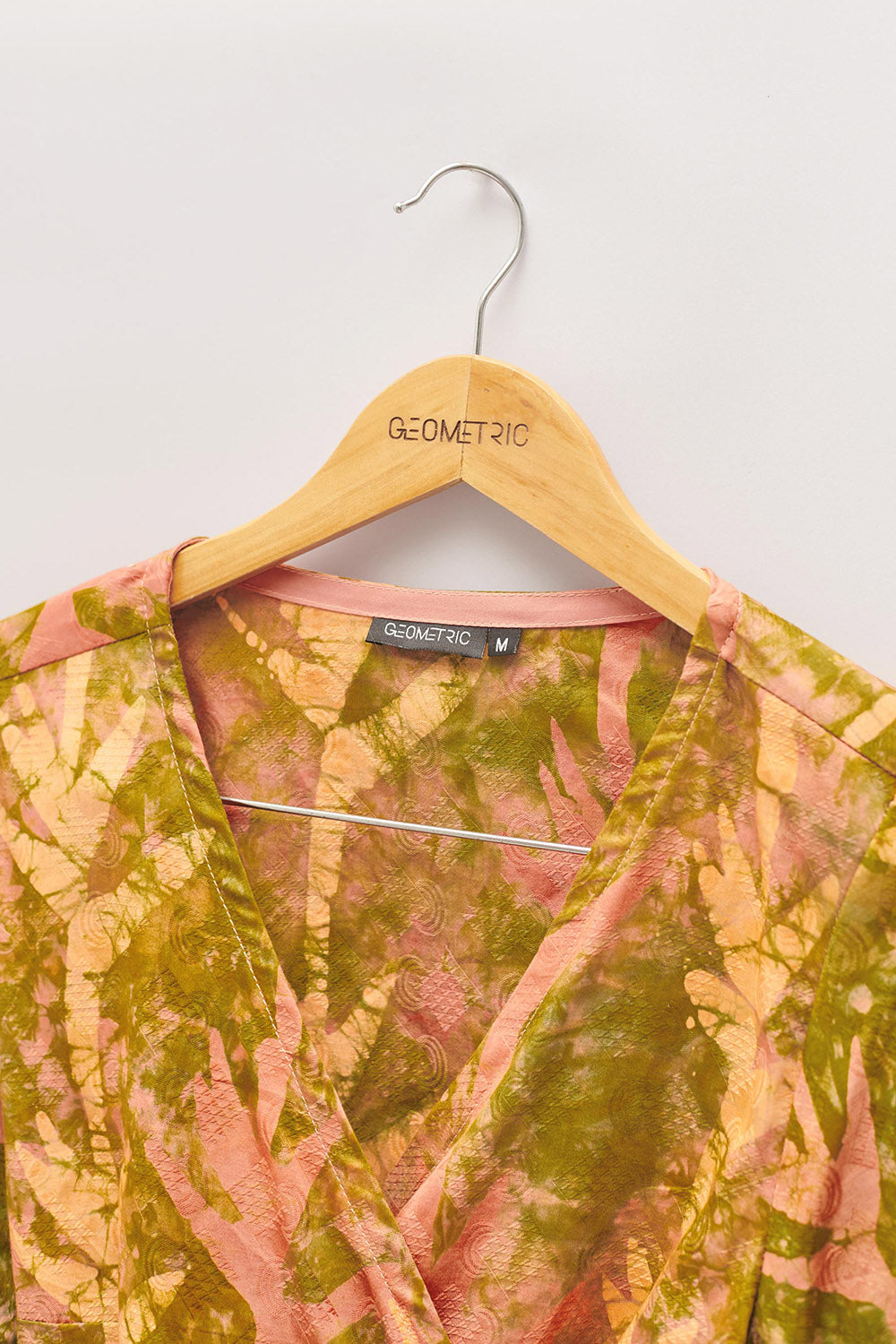 Close-up of hand-dyed orange Birds of Paradise batik print long sleeve wrap top by GEOMETRIC. 