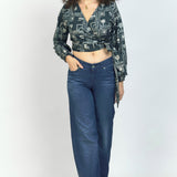 Woman wearing jeans and charcoal hand-dyed batik Coco print long sleeve wrap top by GEOMETRIC. 