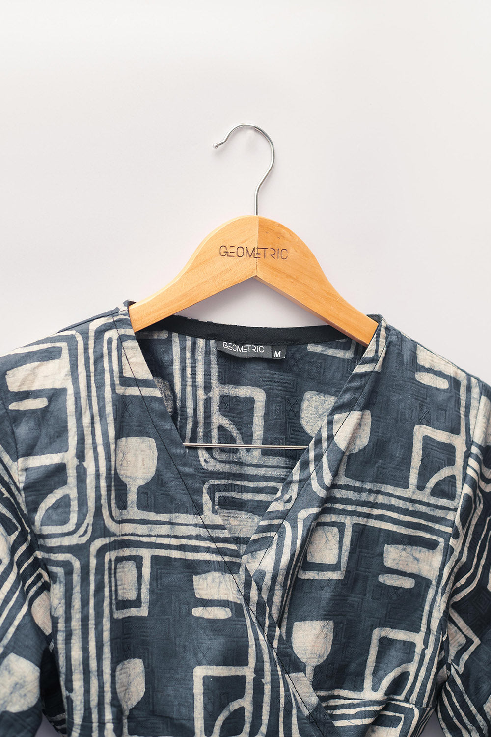 Close-up of charcoal hand-dyed batik Coco print long sleeve wrap top by GEOMETRIC. 