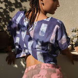 Back view of woman wearing crop wrap top by Geometric made from purple tone hand dyed deadstock fabric. 