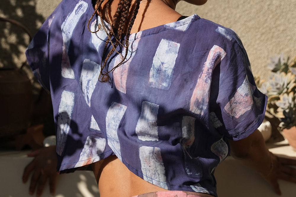 Back view of woman wearing crop wrap top by Geometric made from purple tone hand dyed deadstock fabric. 