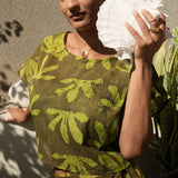 Woman holding shell wearing matching crop wrap top and wrap skirt by Geometric green tone hand dyed deadstock fabric. 