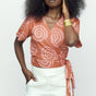 Woman wearing hand-dyed pink and orange Shea Shell dot batik print Short Sleeve Wrap Top by GEOMETRIC. 