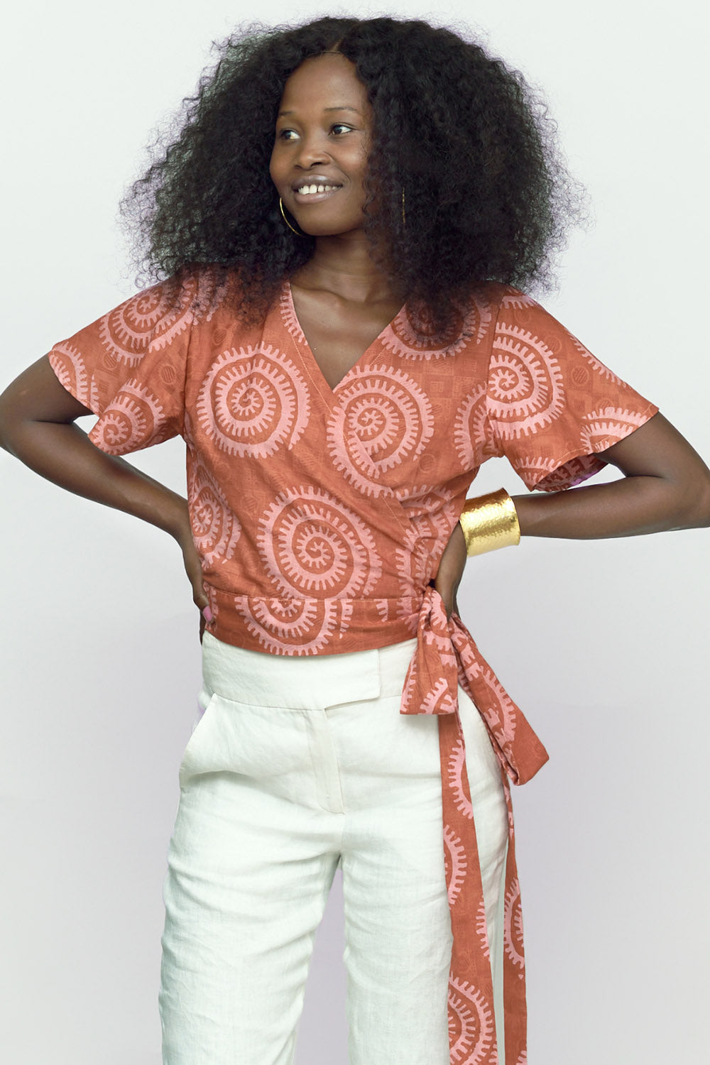 Woman wearing hand-dyed pink and orange Shea Shell dot batik print Short Sleeve Wrap Top by GEOMETRIC. 