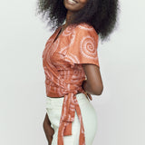 Woman wearing hand-dyed pink and orange Shea Shell dot batik print Short Sleeve Wrap Top by GEOMETRIC. 