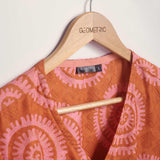 Close-up of hand-dyed pink and orange Shea Shell dot batik print Short Sleeve Wrap Top by GEOMETRIC. 