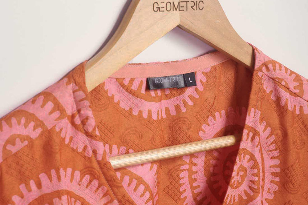 Close-up of hand-dyed pink and orange Shea Shell dot batik print Short Sleeve Wrap Top by GEOMETRIC. 