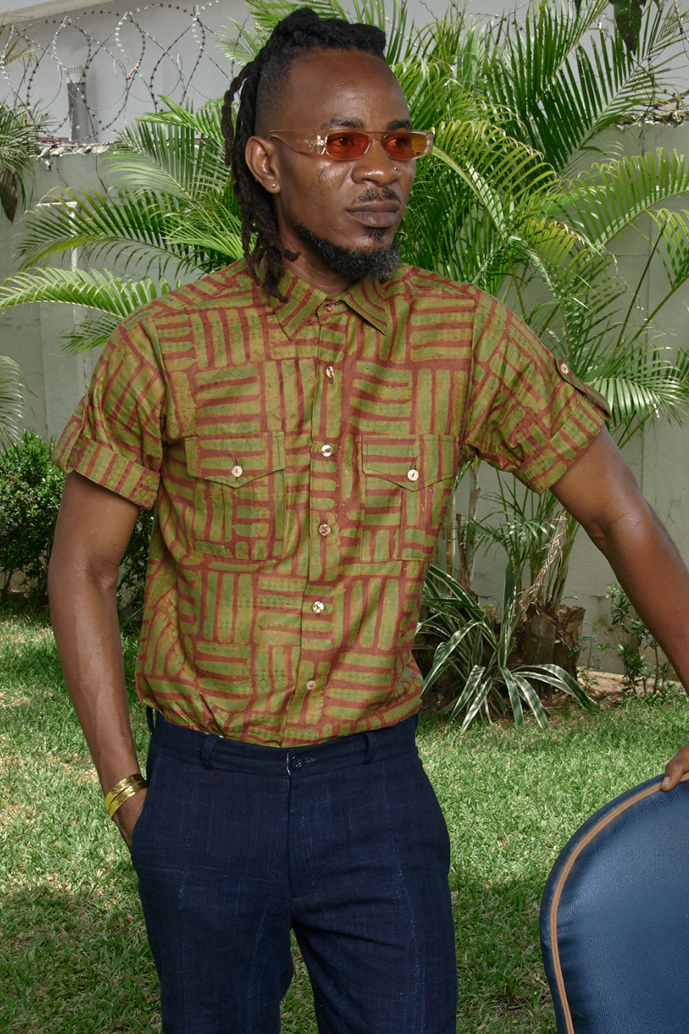 Man wearing hand-dyed green batik Garden Gate print short sleeve button up shirt by GEOMETRIC. 