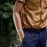 Man wearing blue shorts and hand-dyed green batik Garden Gate print short sleeve button up shirt by GEOMETRIC. 
