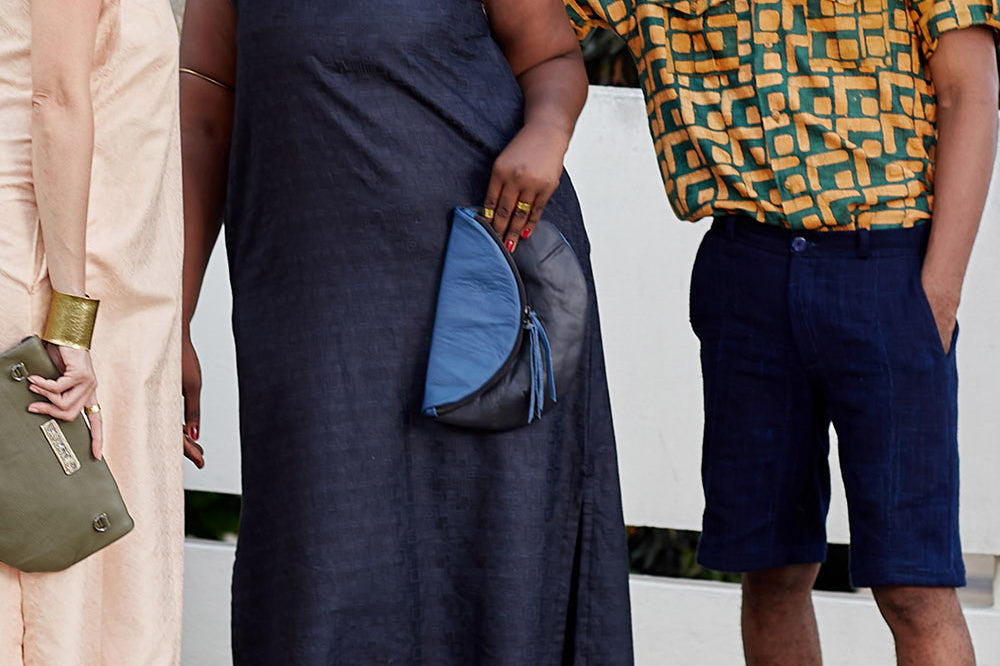 Two women in maxi dresses and a man wearing blue shorts and hand-dyed green and gold batik print short sleeve button up shirt by GEOMETRIC. 