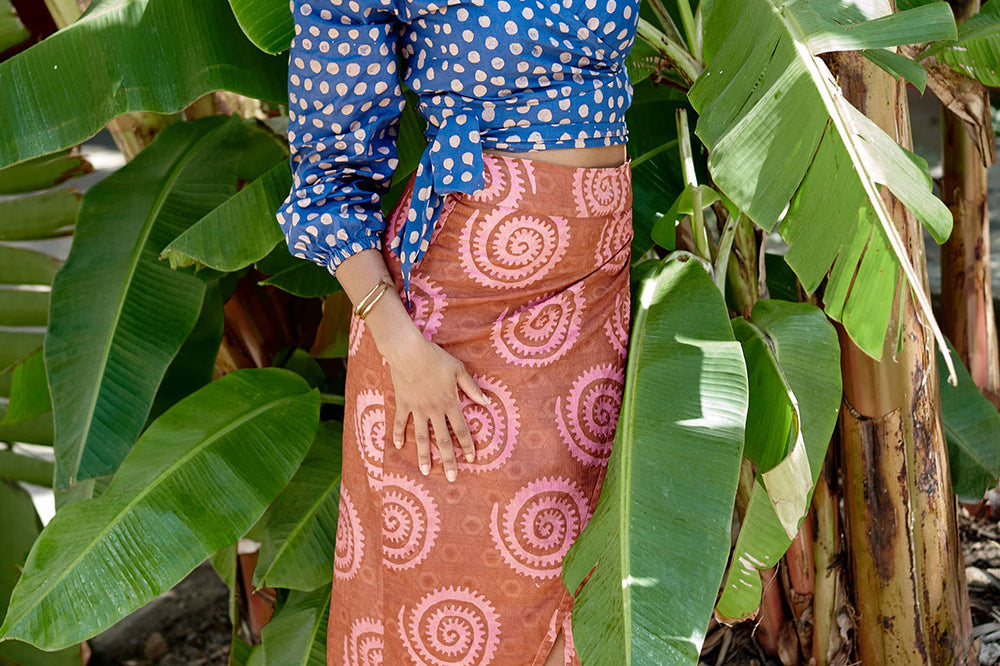 Woman wearing blue polka dot and orange and red hand-dyed wrap skirt by GEOMETRIC. 